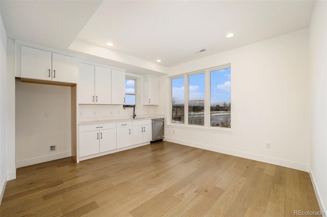 kitchen featuring stainless steel dishwasher, white cabinets, and light hardwood / wood-style flooring