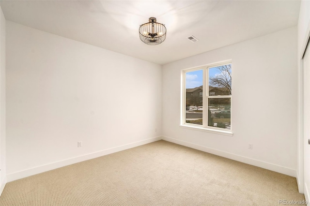 carpeted spare room featuring a chandelier