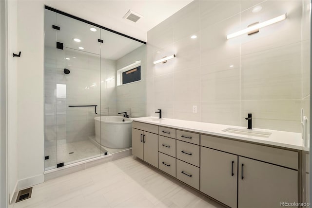 bathroom with vanity, independent shower and bath, and tile walls