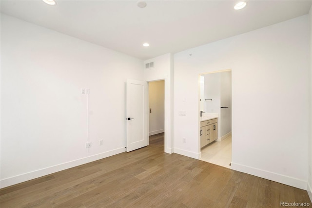 unfurnished bedroom featuring light wood-type flooring and connected bathroom