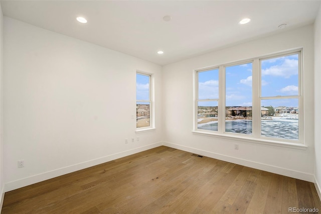 unfurnished room featuring hardwood / wood-style flooring and a healthy amount of sunlight