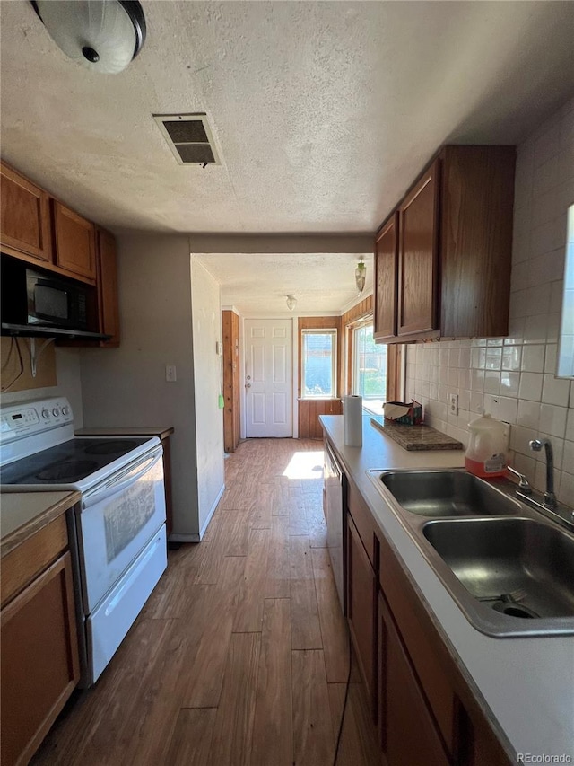 kitchen with backsplash, sink, wood-type flooring, electric stove, and a textured ceiling