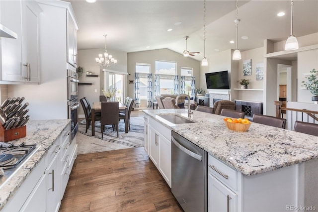 1177 Man O War Way, Colorado Springs, CO 80921 - kitchen with stainless steel appliances, vaulted ceiling, a ceiling fan, a center island with sink, and white cabinetry