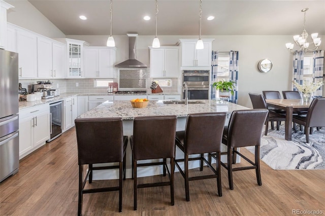 1177 Man O War Way, Colorado Springs, CO 80921 - kitchen featuring wall chimney exhaust hood, wine cooler, stainless steel appliances, a kitchen breakfast bar, and decorative backsplash