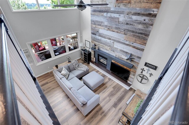 10822 Eagle Crest Ct, Parker, CO 80138 - living area with a high ceiling, wood walls, a fireplace, a ceiling fan, and wood finished floors