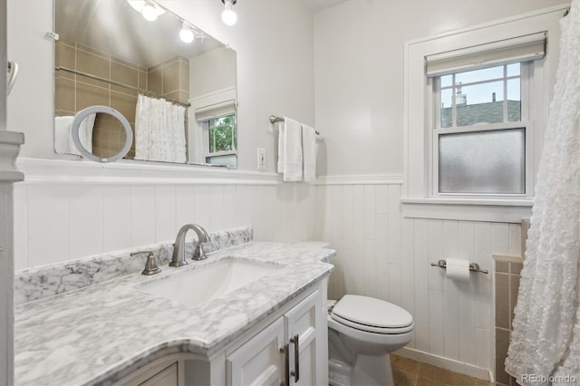 1870 S Ogden St, Denver, CO 80210 - bathroom with wainscoting, toilet, vanity, healthy amount of natural light, and tile patterned flooring