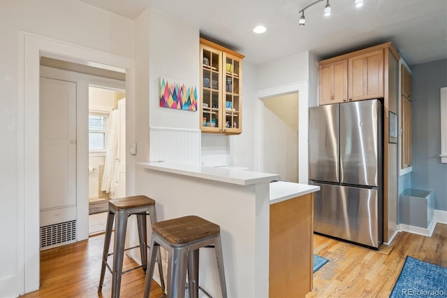 1870 S Ogden St, Denver, CO 80210 - kitchen with freestanding refrigerator, a breakfast bar area, light wood-style flooring, and glass insert cabinets