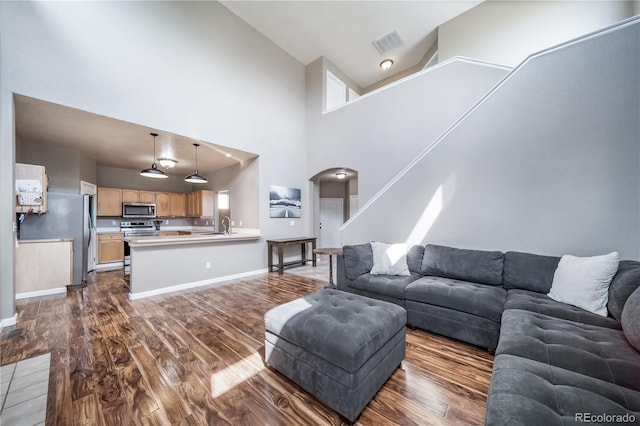 13152 E 104th Dr, Commerce City, CO 80022 - living area with arched walkways, dark wood-style flooring, and a towering ceiling