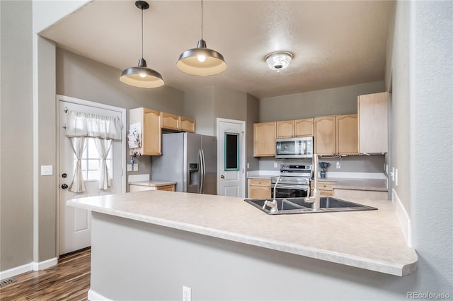 13152 E 104th Dr, Commerce City, CO 80022 - kitchen with stainless steel appliances, light brown cabinetry, a peninsula, dark wood finished floors, and light countertops