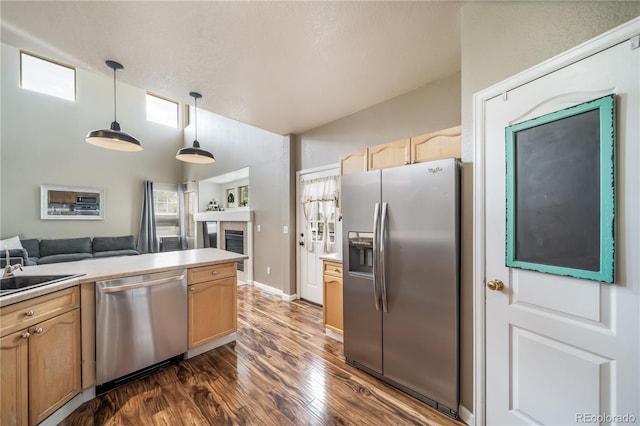 13152 E 104th Dr, Commerce City, CO 80022 - kitchen with appliances with stainless steel finishes, dark wood-style floors, a tiled fireplace, decorative light fixtures, and light countertops