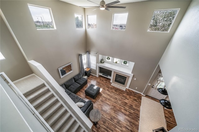13152 E 104th Dr, Commerce City, CO 80022 - living room featuring a ceiling fan, a towering ceiling, a fireplace, stairs, and wood finished floors