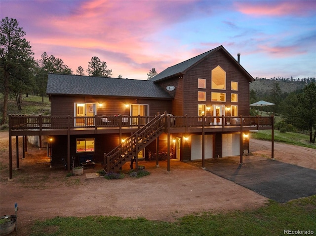 15608 Ouray Rd, Pine, CO 80470 - rear view of property featuring driveway, a garage, a wooden deck, stairs, and roof with shingles