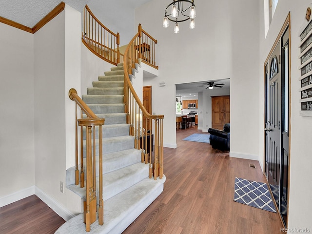 2145 Wynterbrook Dr, Highlands Ranch, CO 80126 - foyer entrance featuring ornamental molding, a towering ceiling, stairway, a chandelier, and wood finished floors