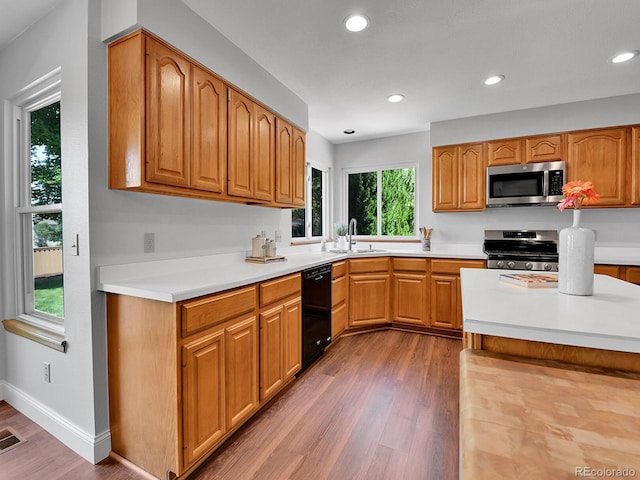 2145 Wynterbrook Dr, Highlands Ranch, CO 80126 - kitchen with appliances with stainless steel finishes, wood finished floors, light countertops, recessed lighting, and brown cabinetry