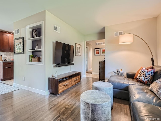 living room featuring light hardwood / wood-style flooring and built in shelves