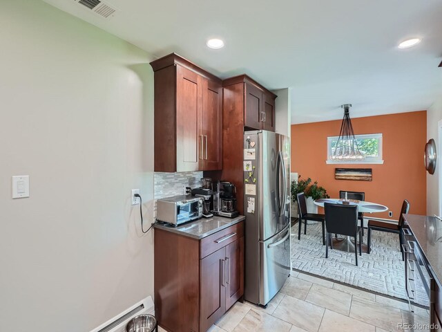 kitchen with decorative backsplash, hanging light fixtures, a baseboard radiator, light tile patterned floors, and stainless steel refrigerator