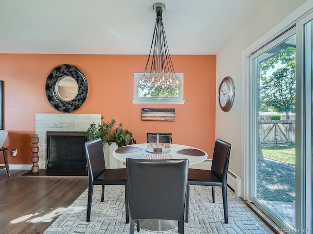 dining room with a chandelier, baseboard heating, and hardwood / wood-style floors