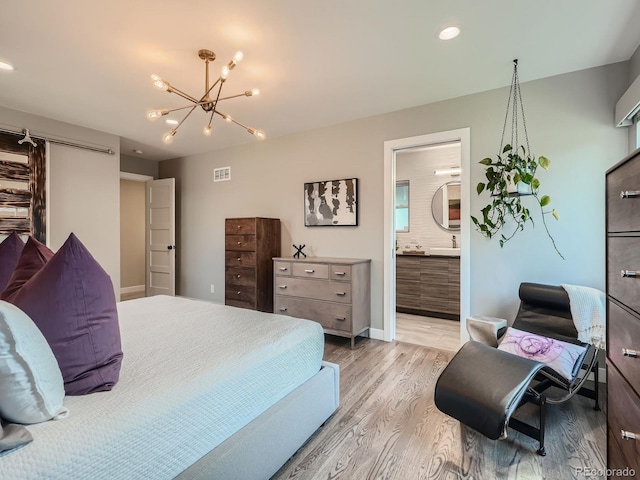 bedroom featuring sink, ensuite bath, light hardwood / wood-style flooring, and a chandelier