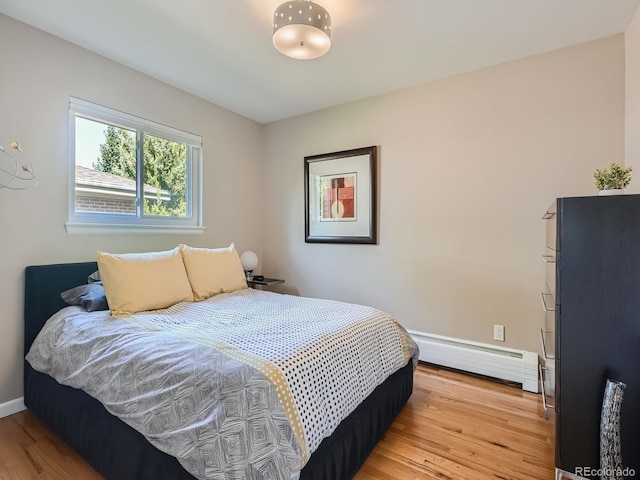 bedroom featuring light hardwood / wood-style flooring and a baseboard heating unit