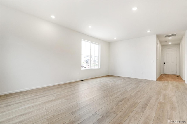 spare room featuring light wood finished floors, recessed lighting, and baseboards