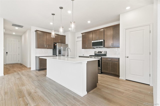 kitchen with stainless steel appliances, a sink, light wood finished floors, light countertops, and recessed lighting