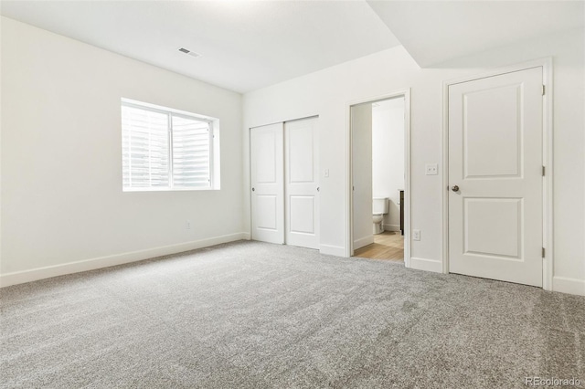 unfurnished bedroom with carpet, baseboards, ensuite bath, and a closet