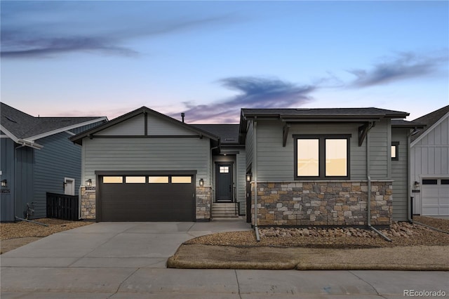 view of front of house with a shingled roof, an attached garage, concrete driveway, and stone siding