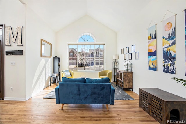 living area featuring high vaulted ceiling, baseboards, and wood finished floors