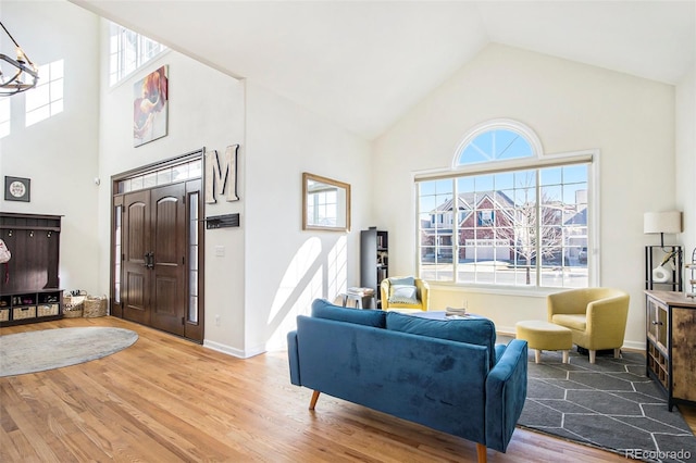 interior space featuring high vaulted ceiling, a notable chandelier, baseboards, and wood finished floors