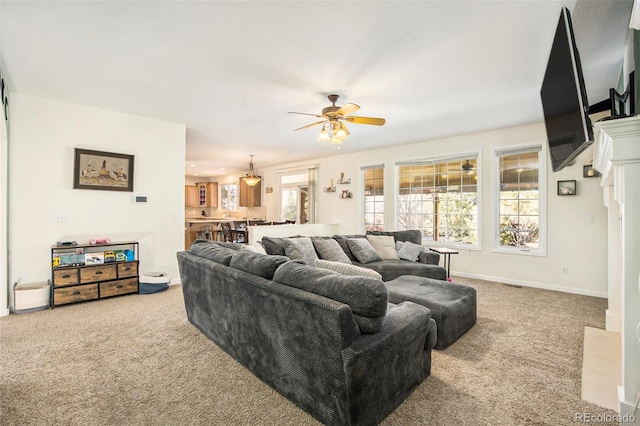 living area featuring carpet floors, ceiling fan, and baseboards