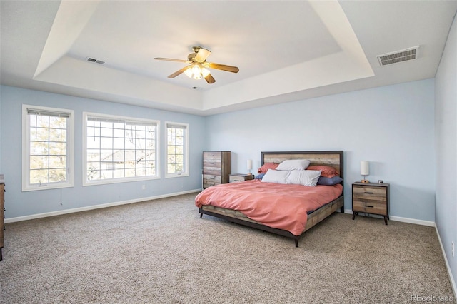 carpeted bedroom with baseboards, visible vents, and a raised ceiling