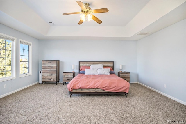 bedroom with carpet floors, baseboards, visible vents, and a tray ceiling