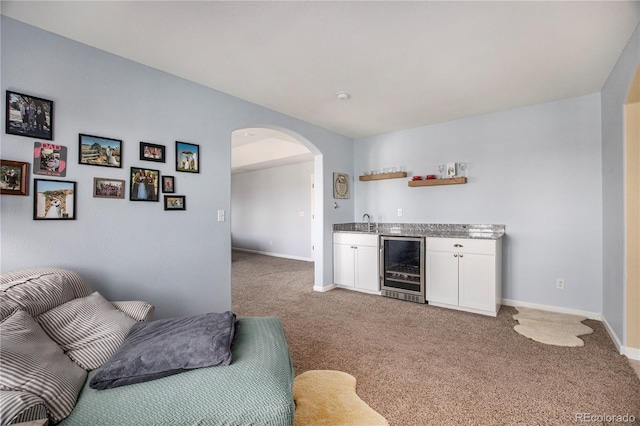 interior space with light carpet, arched walkways, wine cooler, white cabinetry, and open shelves