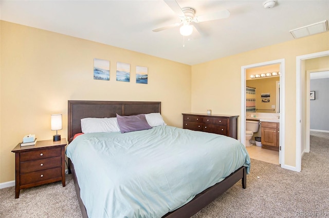 bedroom featuring visible vents, baseboards, a ceiling fan, light colored carpet, and ensuite bath