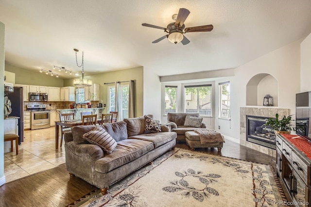 3143 50th Avenue Ct, Greeley, CO 80634 - living area with a tiled fireplace, ceiling fan, light wood-style flooring, and lofted ceiling