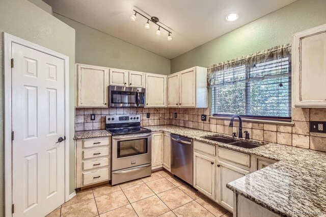 3143 50th Avenue Ct, Greeley, CO 80634 - kitchen with appliances with stainless steel finishes, vaulted ceiling, tasteful backsplash, light tile patterned flooring, and light stone countertops