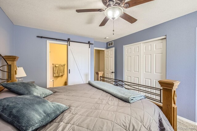 3143 50th Avenue Ct, Greeley, CO 80634 - carpeted bedroom with a closet, a barn door, ceiling fan, and a textured ceiling