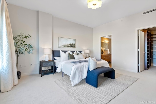 bedroom featuring a walk in closet, ensuite bathroom, and carpet