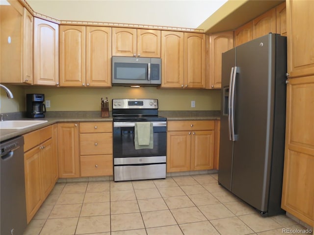kitchen featuring stainless steel appliances, light brown cabinets, a sink, and light tile patterned floors