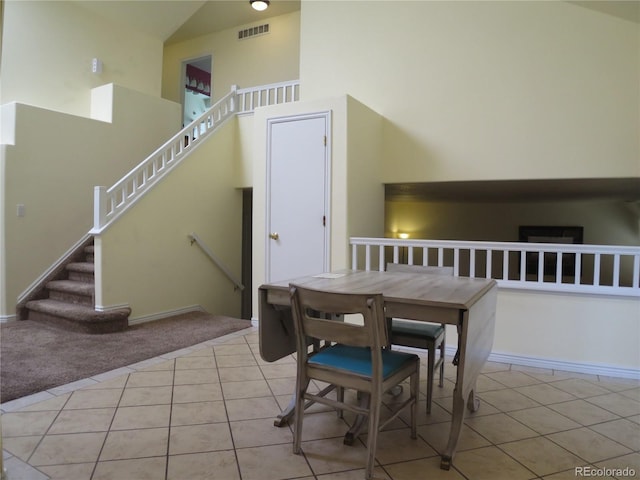 dining area with high vaulted ceiling, light carpet, light tile patterned flooring, and visible vents