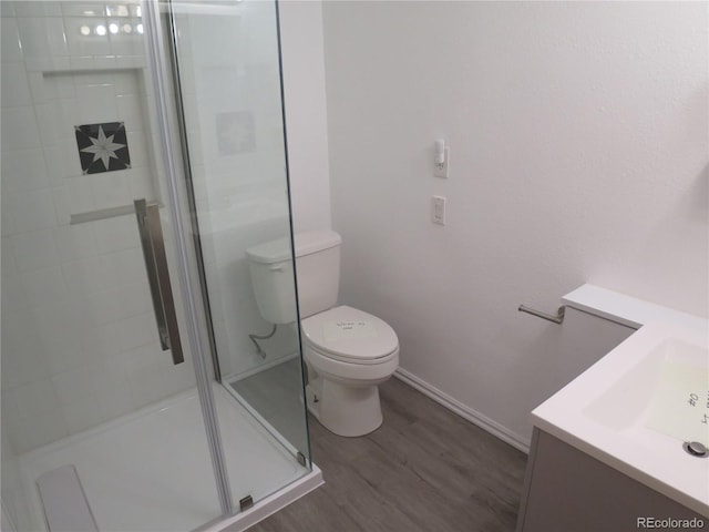 full bathroom with a shower stall, wood finished floors, toilet, vanity, and baseboards