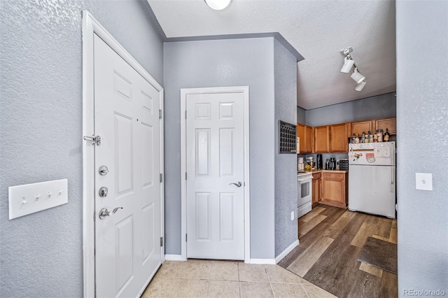 10787 Twenty Mile Rd Unit 205, Parker, CO 80134 - kitchen with freestanding refrigerator, electric stove, a textured wall, a textured ceiling, and light tile patterned floors