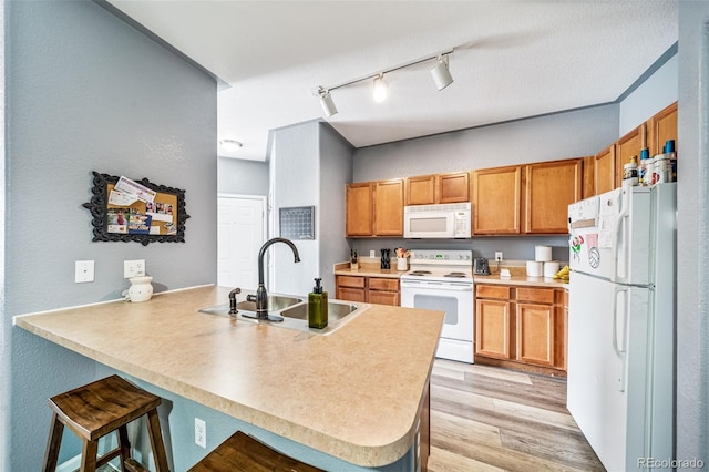 10787 Twenty Mile Rd Unit 205, Parker, CO 80134 - kitchen featuring white appliances, a sink, a peninsula, a breakfast bar area, and rail lighting