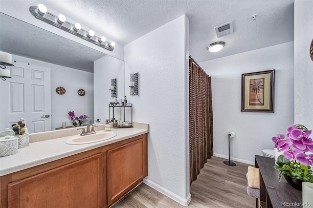 10787 Twenty Mile Rd Unit 205, Parker, CO 80134 - full bathroom featuring vanity, wood finished floors, a textured ceiling, baseboards, and a textured wall