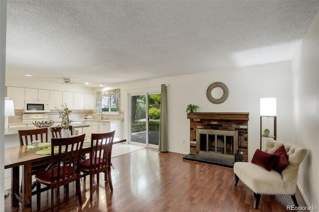 10883 Otis Cir, Westminster, CO 80020 - dining space featuring dark wood finished floors, a textured ceiling, a brick fireplace, and ceiling fan