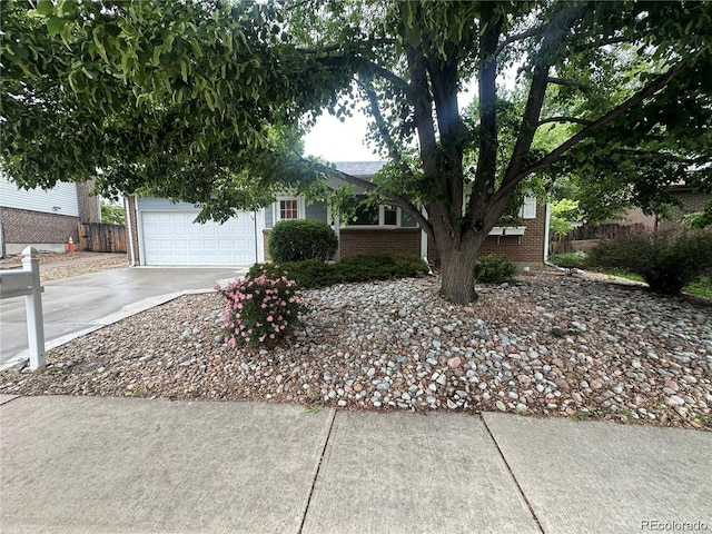 10883 Otis Cir, Westminster, CO 80020 - view of property hidden behind natural elements with driveway, brick siding, and an attached garage