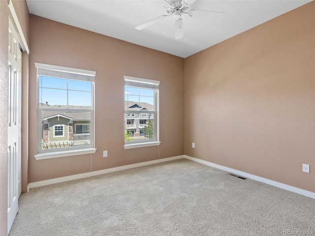 empty room with ceiling fan and light colored carpet