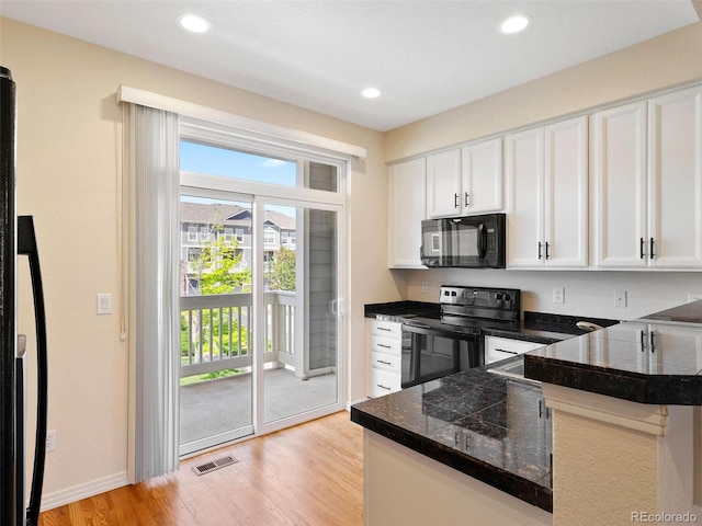 kitchen with kitchen peninsula, white cabinetry, black appliances, and light hardwood / wood-style floors