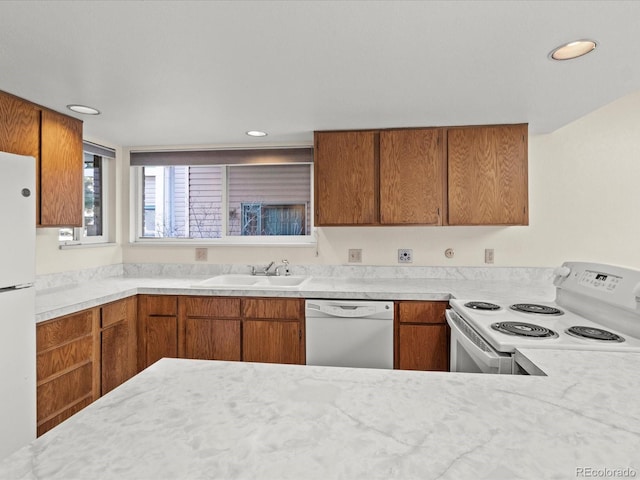 kitchen featuring recessed lighting, white appliances, a sink, light countertops, and brown cabinets