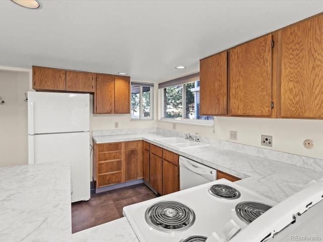 kitchen with light countertops, white appliances, a sink, and brown cabinets